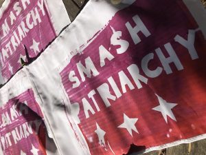 A series of posters on a wall saying "Smash Patriarchy" 