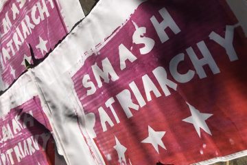 A series of posters on a wall saying "Smash Patriarchy"
