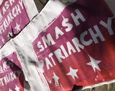 A series of posters on a wall saying "Smash Patriarchy"