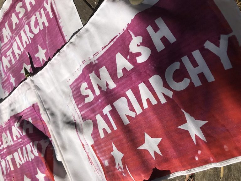 A series of posters on a wall saying "Smash Patriarchy"